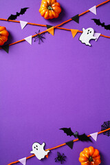 Wall Mural - Halloween spooky decorations, garland, pumpkins, ghosts, bat, spiders on purple background. Flat lay, top view, vertical.