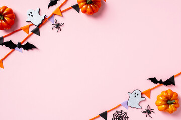 Wall Mural - Happy Halloween holiday concept. Flat lay composition with paper garland, pumpkins, bats, ghosts, spiders on pastel pink background. Top view with copy space