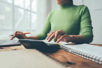 Financial Focus: A woman diligently manages her finances, calculating expenses with a focused expression, her hands gracefully navigating a calculator and notepad. 