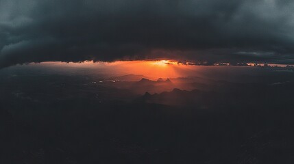 Wall Mural - sun shining on mountain range through dark clouds in distance