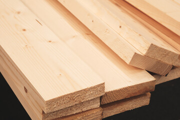 Poster - A pile of wood with a black background. The wood is stacked in a way that it looks like it's about to fall