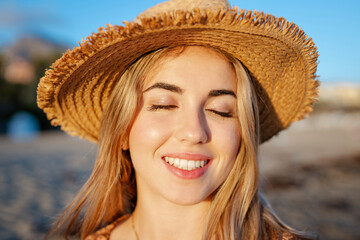 Wall Mural - Portrait of one happy beautiful woman on the sand of the beach enjoying and having fun at the sunset of the day. Looking at the camera smiling..