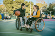 © Irina B - Two women in wheelchairs smiling and enjoying a basketball game on an outdoor court.