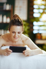 Poster - woman in spa salon using phone and laying on massage table