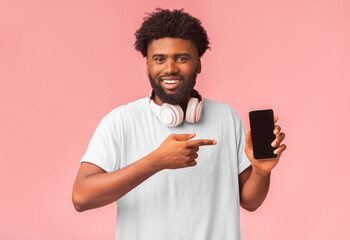 Poster - I recommend cellphone. Modern african american guy pointing at newest mobile phone with blank screen, pink background with empty space