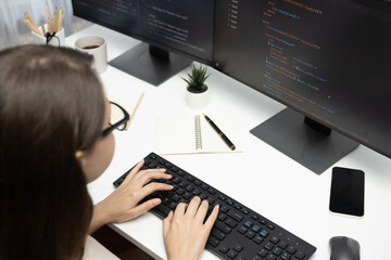 Wall Mural - IT developer woman coding on laptop screen at back side view, creating social media website system automatically reply to customer, thinking program update data center at modern office. Postulate.