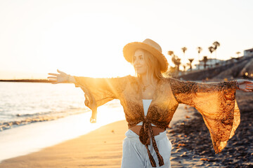 Wall Mural - One happy beautiful woman walking on the sand of the beach enjoying and having fun at the sunset of the day. Looking at the sea smiling..