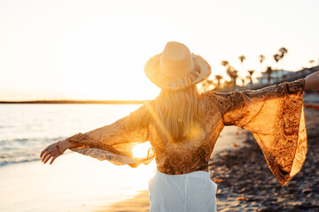 Wall Mural - One happy beautiful woman walking on the sand of the beach enjoying and having fun at the sunset of the day. Leisure time on vacations, freedom concept.