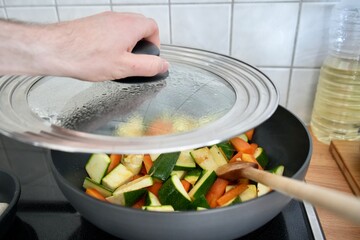 Person cooking fresh vegetables in the pan