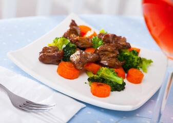 Portion of fried chicken hearts with garnish of boiled vegetables