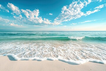 Wall Mural - Foamy Ocean Waves Crashing on a Sandy Beach Under a Blue Sky with White Clouds