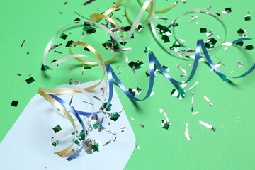 Poster - Shiny confetti, party streamers and envelope on green background, closeup