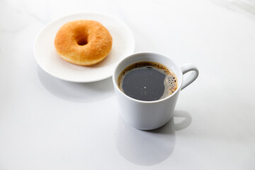 Cup of black coffee, Donut on white marble background. Copy space.