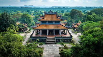 Traditional Asian temple with tiered roofs surrounded by lush green trees and hills under a clear blue sky.