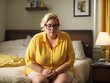 © shrinay - plus size senior female in yellow shirt  sitting on bed in bedroom