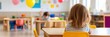 © gunzexx png and bg - A young child is sitting alone at a table in a colorful and well-decorated kindergarten classroom, focusing on an activity in a bright, educational environment.