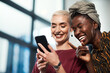 © Malambo/peopleimages.com - Business, women and pointing with laughing at phone for social media meme, internet joke or funny text message. Creative designer, team and comedy video on smartphone with streaming service in office