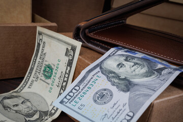 A leather wallet with dollar bills lies on paper boxes.