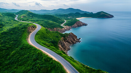 Aerial view of a winding road along a scenic coastline with lush green hills and turquoise waters.