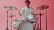 © Paisan - A Young Musician Enthusiastically Playing His Drum Set Against a Vibrant Pink Backdrop. Man and Music Concept