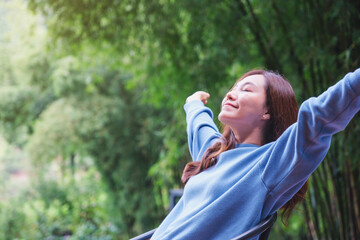 Wall Mural - Portrait image of a woman with arms raised enjoying with green nature