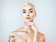 © Malambo/peopleimages.com - Woman, confidence and portrait with skincare in studio for cosmetic beauty, results or facial glow. Person, piercings and tattoo with satisfaction for dermatology, makeup or shine on white background