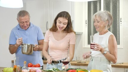 Wall Mural - Positive senior couple spending time together with their adult daughter, cooking delicious meals for dinner