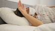 © Traveler0205 - Sick woman wearing mask lying in bed fighting illness. Visible discomfort from virus, cold, fever, cold and fatigue from illness. Lying in bed due to severe illness showing the impact of illness.