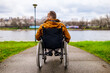 © djoronimo - Rear view image of paraplegic handicapped man in wheelchair by the lake.