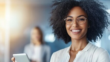 A woman with curly hair is smiling and holding a tablet