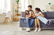 © Studio Romantic - Family fun. Loving parents tease and tickle their preteen daughter while having fun at home. Funny Caucasian young dad, mom and their daughter spending time together sitting on sofa in living room.