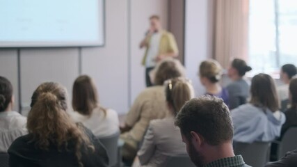 Wall Mural - Group of people attentively listening to a speaker during a business seminar in a modern conference room.