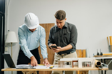 Wall Mural - Two colleagues discussing data working and tablet, laptop with architectural project at construction site