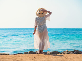 Wall Mural - Woman in a hat on the seashore. Selective focus.