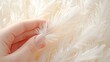 © BOJOShop - Close Up of a Hand Holding a White Feather Against a Background of More Feathers