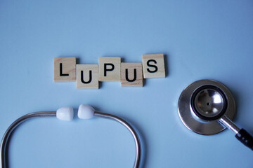 LUPUS, wooden letters with stethoscope on light blue background. medicine concepts