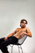 © Alex Vog - Portrait of handsome young man muscular fashion model with muscle abs press posing on chair, looking away. Sporty healthy strong muscle guy with sexy bare torso, ad effect concept. Copy ad text space