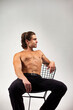 © Alex Vog - Excellent fashion model young muscular man with perfect sexy bare torso sits on chair, positive looking away. Sporty strong guy with muscle abs press on studio white background. Copy ad text space