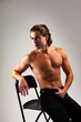 © Alex Vog - Handsome muscular guy with perfect sexy naked muscle abs torso posing on white studio background, sure looking away. Lovely sporty man with muscles abs press on chair in shadow. Copy ad text space
