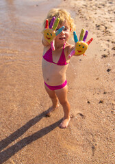 Poster - Child hand paints on the seashore. Selective focus.