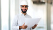 © Anastasia - Happy middle eastern male engineer smiling while holding blueprints in a bright office environment