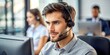 © ivatekstudio - Male call center employee sitting in the office with headphones in front of the computer