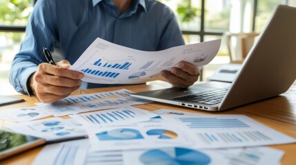 Poster - A business executive analyzing a printed report with various graphs and charts, seated at a desk with a laptop and financial documents scattered around.