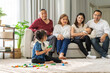 © Art_Photo - Multigenerational asian family spending time together at home, grandparents talking to parents while young girl plays with colorful building blocks on floor, loving family moments, parenting, bonding