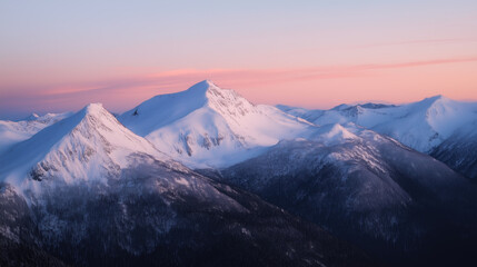 Snow covered mountain peaks glowing pink at sunset