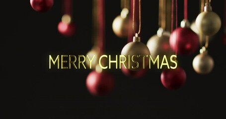 Canvas Print - Merry christmas text in gold over baubles hanging on dark background