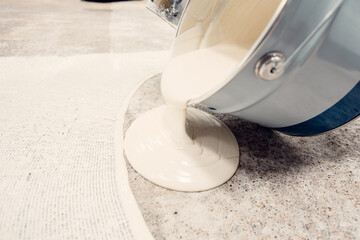 Construction worker pouring self leveling compound on the floor