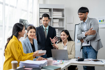 Wall Mural - A group of people are gathered around a table with a laptop, smiling