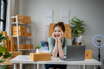 Wall Mural - A woman is sitting at a desk with a laptop and a box of boxes behind her