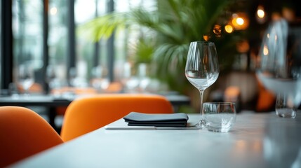 The elegant restaurant table setting is highlighted by orange chairs and a clear wine glass, creating a sophisticated and inviting atmosphere perfect for fine dining.